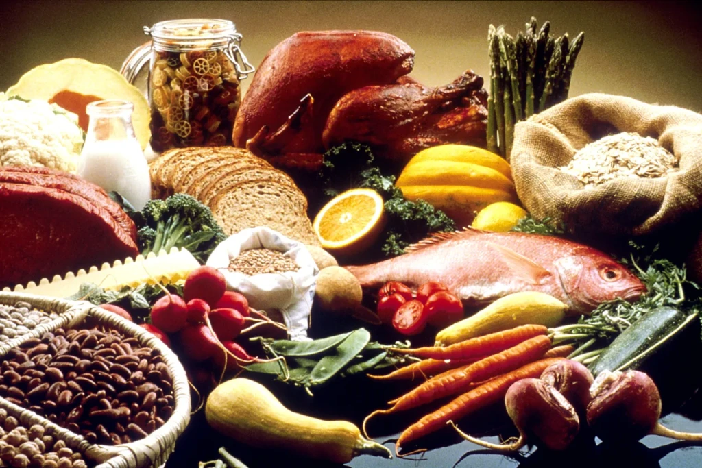 Alimente variate pe o masă: somon, curcan, pâine, paste, fasole, legume și fructe