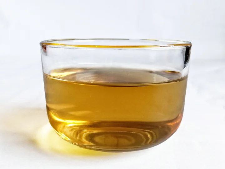 Infuzie de culoare aurie într-un pahar de sticlă, pe fond alb
