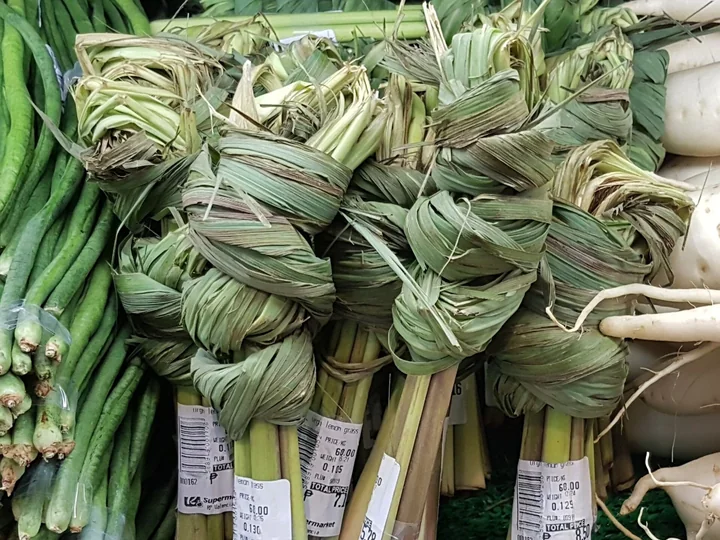 Mănunchiuri de lemongrass la vânzare, cu frunzele împletite și cu bazele palide ale tulpinilor legate laolaltă