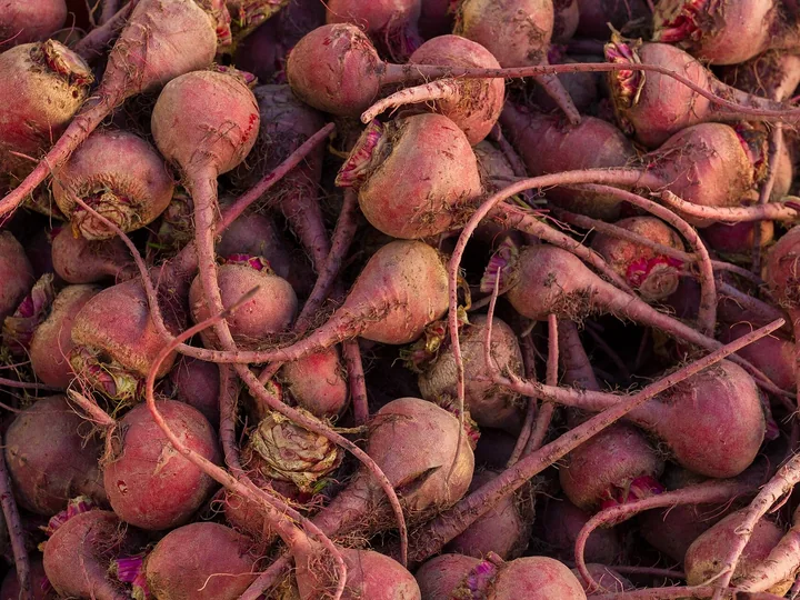 Rădăcini mici de sfeclă roșie-violetă, rotunde, cu codițe lungi și subțiri, într-o grămadă